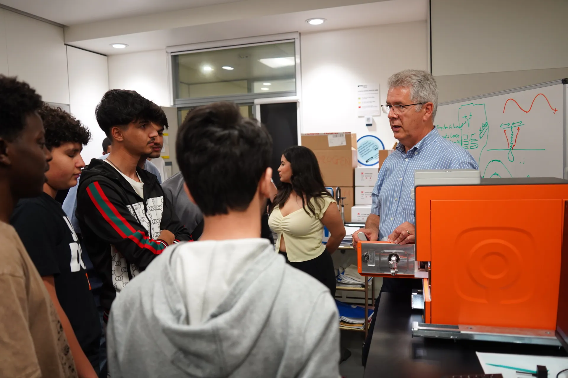 Students gathered round a tabletop electron microscope demonstration